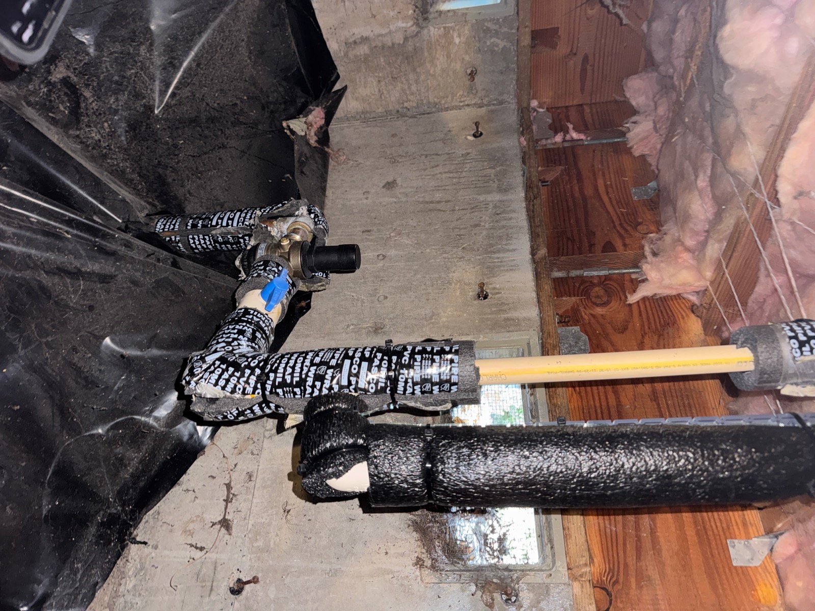 Crawlspace main water line before Moen Flo installation, showing pressure-reducing valve, ball valve and insulated piping